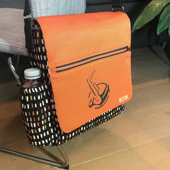 Современная версия сумки-мессенджера с узорами, оранжевым клапаном на молнии и корзиной для напитков.